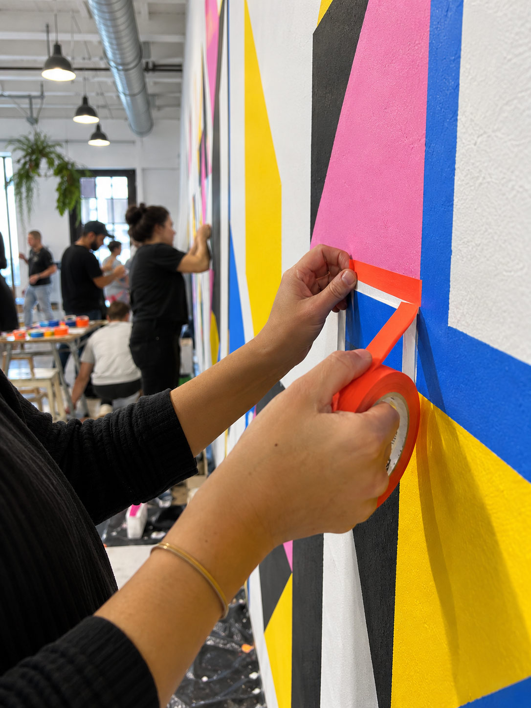 Hands applying coloured tape to a wall piece during the workshop