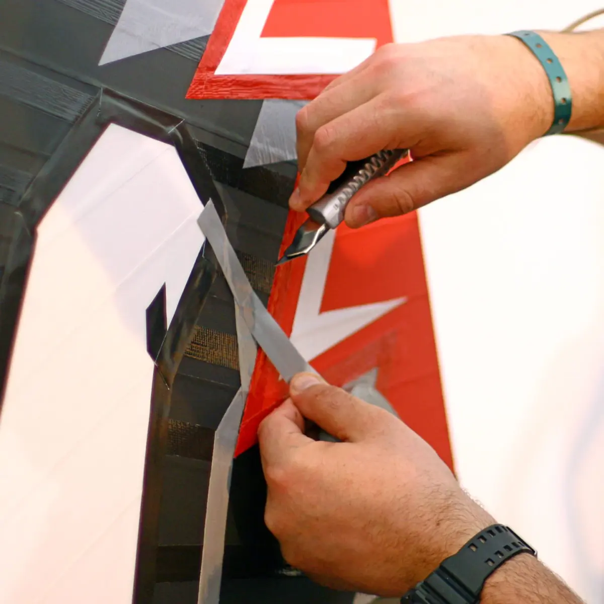 Hands applying tape art to a wall with precision