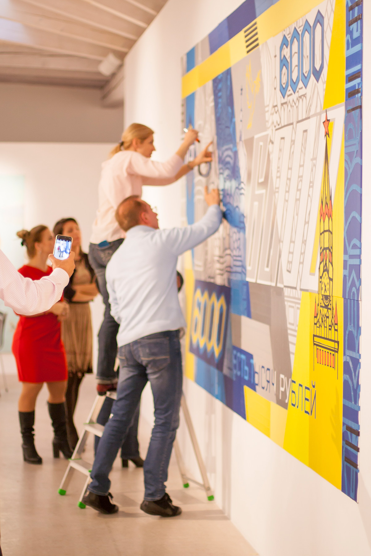 A team taping a tape art mural together in a workshop
