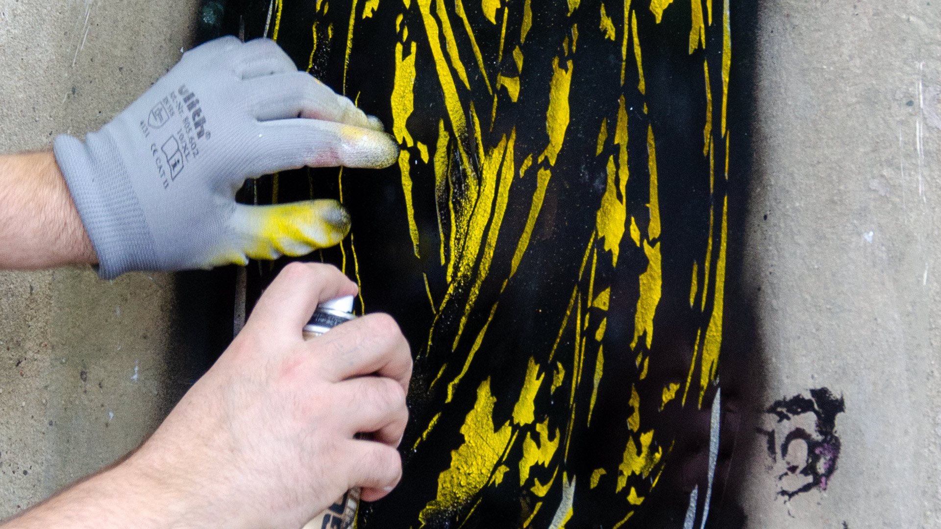 Hand spraying a stencil motif on a wall
