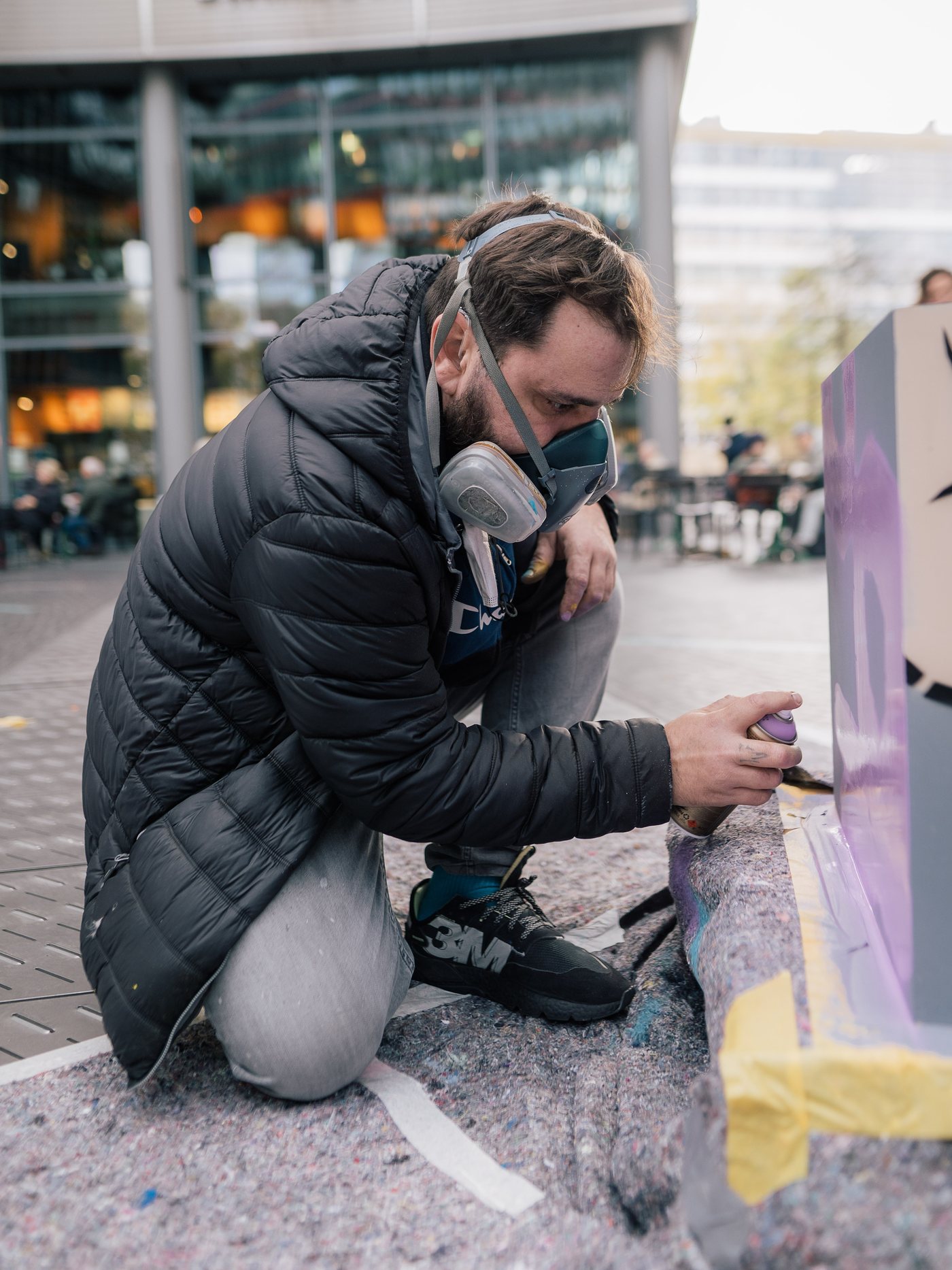 Slava Osinski wearing a respirator while spraying a stencil in the city